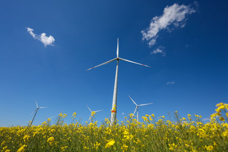 Large windmill turbines in a field with blue sky. Windmill field in the countryside in Europe.