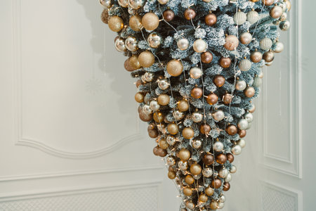 An elegantly designed upsidedown Christmas tree decorated with gold, silver, and bronze ornaments serves as a stunning modern focal point for the holiday seasonの写真素材