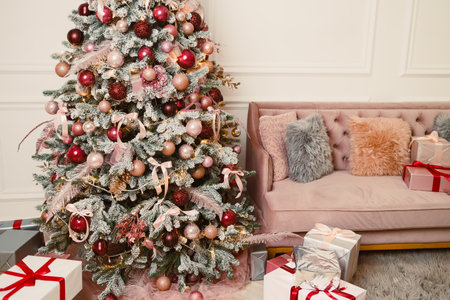 Imagine a cozy holiday scene with a lavishly decorated Christmas tree, adorned with glimmering ornaments and surrounded by beautifully wrapped gifts in a joyful living roomの写真素材