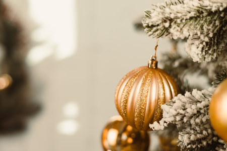 Golden Christmas ornaments adorn a snowdusted evergreen tree, creating a stunning display that captures a festive and elegant holiday atmosphere for celebrating with loved onesの写真素材
