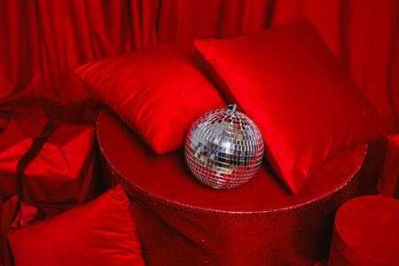 This scene showcases a striking arrangement with rich red fabrics, plush pillows, and a dazzling disco ball overhead, creating a festive atmosphere for celebrationの写真素材