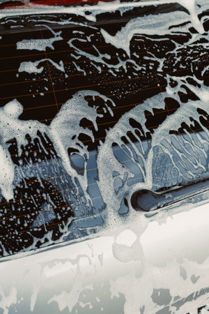 This image offers a closeup view of the luxurious foam covering a car, emphasizing the meticulous process involved in washing and maintaining the vehicles cleanliness and shineの写真素材