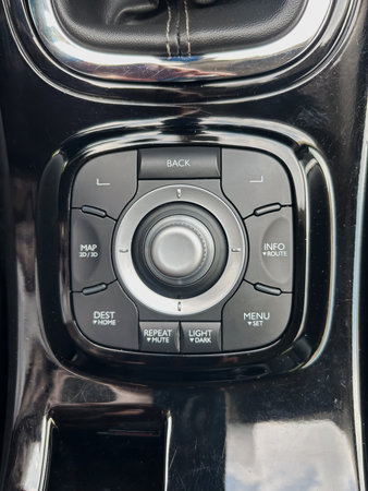 This image shows a closeup of a modern cars control panel, featuring a multimedia dial and buttons...