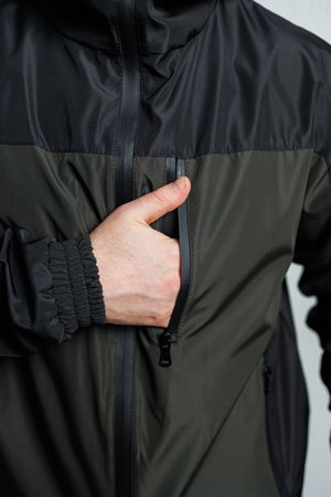 Closeup shot of a man prominently showcasing the zipper pocket on an elegantly designed athletic...