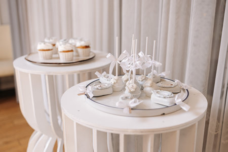 A stunning dessert display features white cupcakes and beautifully decorated cake pops, ideal for weddings, birthdays, or any elegant event needing a sweet touchの写真素材