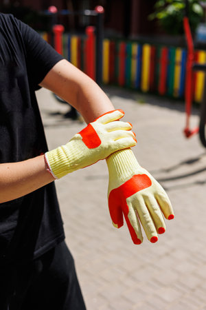 A person puts on bright yellow and orange gloves, ready for outdoor work or gardening, showing commitment to safety and thorough preparation for the task aheadの写真素材