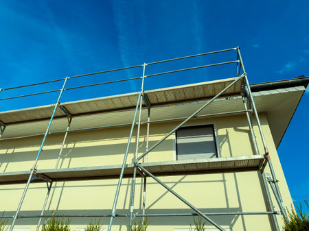 A wellstructured scaffolding system on a residential building showcases active construction against a clear blue sky, ideal for highlighting renovation projectsの写真素材