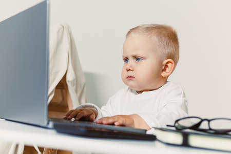 A baby focused on a laptop highlights the trend of early tech familiarity in children, reflecting broader themes of technology, education, and modern parentingの写真素材