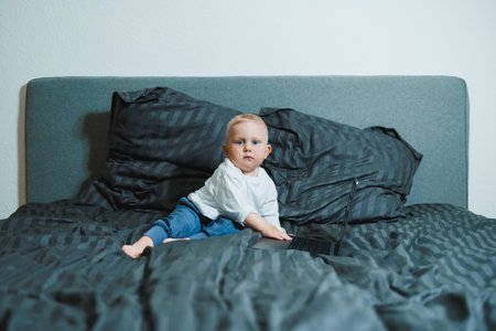 A curious toddler sits on a soft bed with colorful bedding, wideeyed and excited as they explore...