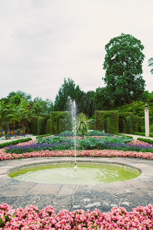 This beautifully designed garden features a stunning central fountain and vibrant flower beds, perfect for outdoor relaxation and breathtaking nature photographyの写真素材