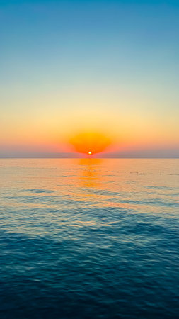 A breathtaking sunset gracefully casts warm hues over the tranquil waters, creating a serene and...