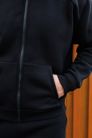 This closeup view showcases a stylish black hoodie with a fashionable zipper and front pocket, ideal...