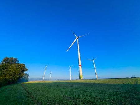 A picturesque landscape with wind turbines under a blue sky highlights the benefits of renewable...