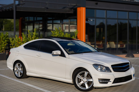 In a contemporary urban environment, a very stylish white MercedesBenz coupe can be seen parked, showcasing its sleek lines and premium craftsmanship thats truly impressiveの写真素材
