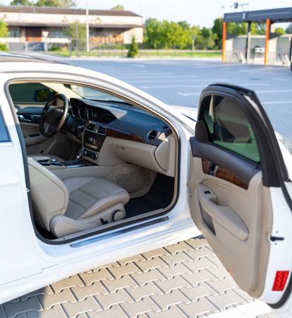 Explore the stylish interior of a luxurious white sedan featuring modern design, comfortable seating, and a contemporary dashboard, showcased in an outdoor location.の写真素材