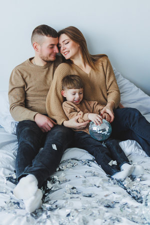 In a heartwarming scene, a loving family is enjoying wonderful quality time on a cozy bed, celebrating love and togetherness through playful moments filled with laughter and joyの写真素材