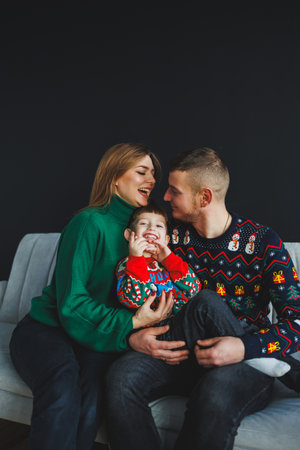 A heartwarming family portrait shows loving parents and their adorable child in colorful Christmas sweaters, highlighting their affection and togetherness this festive seasonの写真素材