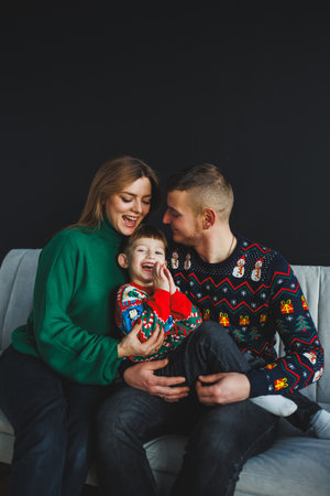 A happy family wearing festive sweaters shares a moment of joy together, radiating warmth and love in a stylish studio environmentの写真素材