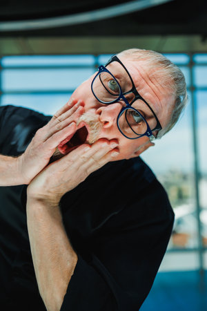 A quirky man with stylish glasses displays a humorous, surprised expression, adding a playful vibe to the contemporary office, illustrating joy in everyday work lifeの写真素材