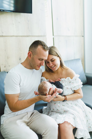 In a warm and serene living room, a loving couple lovingly admires their precious newborn baby, beautifully showing the profound joy and bonds of family togethernessの写真素材