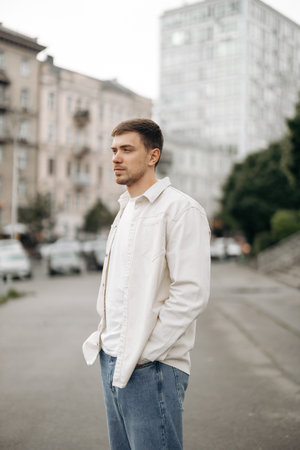 A stylish young man stands confidently on an urban street, wearing a trendy outfit that embodies...