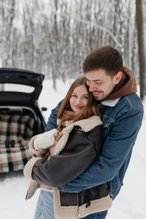A joyful couple is seen embracing in a serene winter setting, surrounded by snowcovered trees that beautifully capture their love and warmth amidst the chilly outdoor atmosphereの写真素材