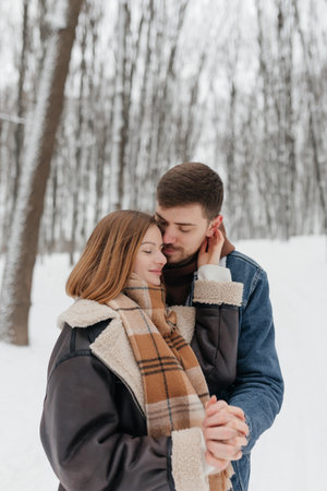 A loving couple is seen sharing a truly tender moment in a beautifully snowcovered forest, showcasing their deep romance and warmth amidst the winters chilly atmosphereの写真素材