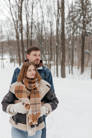 A cozy couple is enjoying a peaceful winter day while being surrounded by beautiful snowcovered trees, showing their love and warmth amidst the distinctly chilly weatherの写真素材