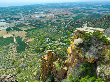 A breathtaking landscape unfolds as lush green fields meet rugged cliffs, showcasing vibrant valleys and distant hills under vast skies. Nature's beauty captivates the soul.の写真素材