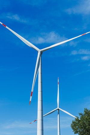 Wind turbines tower above, their blades rotating smoothly as they harness the power of the wind. The scene is peaceful, showing renewable energy and nature in harmony.の写真素材