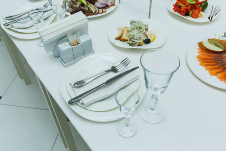 A beautifully arranged dining table exquisite features plates with various culinary delights, fine cutlery, and elegant glassware, setting the stage for a memorable dining experience.の写真素材