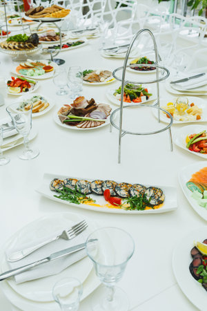 A stunning array of colorful dishes fills a large white table, showcasing seafood, meats, salads, and desserts. Guests enjoy a lively atmosphere in bright, natural light.の写真素材