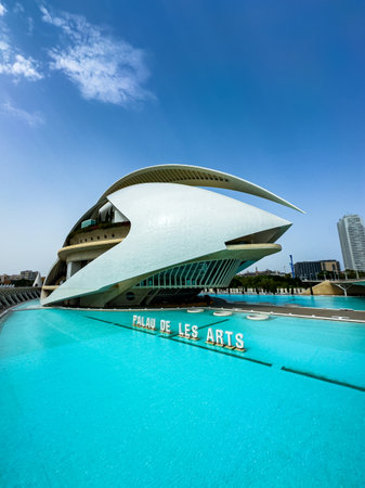 Palau de les Arts stands proudly in Valencia, showing its unique design besides vibrant turquoise water. The bright day enhances its striking architecture, inviting exploration and admiration.の写真素材