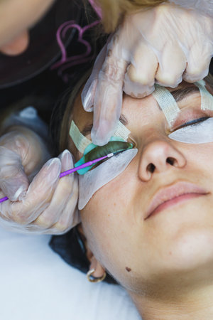 A skilled beautician carefully applies eyelash extensions to a client's eyes in a calm and relaxing spa environment, creating a serene atmosphere during the beauty treatment.の写真素材