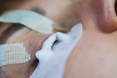 An eye is gently prepared for eyelash extensions, showing the meticulous work of a beauty professional using specialized tools. The serene atmosphere enhances relaxation.の写真素材
