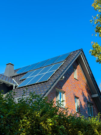 A contemporary home showcases solar panels atop a sloped roof, nestled among vibrant greenery, with...