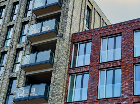 Tall apartment buildings feature a mix of brick and textured surfaces, with balconies overlooking...