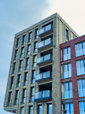 Unique architectural structure features multiple balconies and large windows, reflecting urban style...