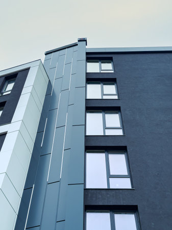 Tall structure features a combination of sleek blue and white panels, with numerous windows...