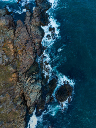 The rugged shoreline reveals a stunning array of rocks as waves crash against them. Sunlight dances...