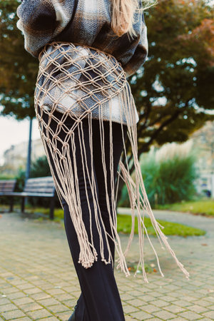 A woman walks confidently in a park, highlighting her beautiful macrame belt. The setting features...