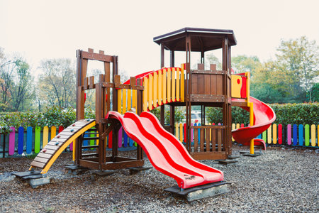 Colorful wooden climbing structure with slides and play areas offers fun for children in a lively...