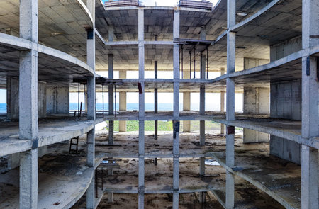 Construction is incomplete on this building with a view of the sea. The concrete framework shows multiple levels and an open design. Grass and ocean are visible through openings.の写真素材