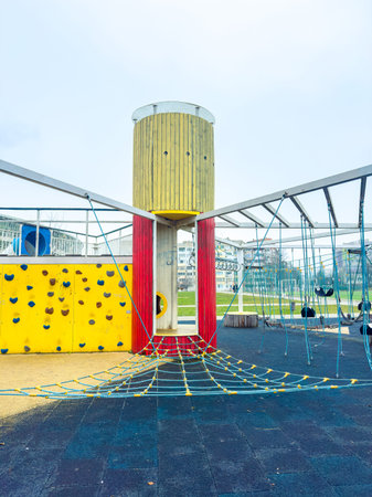 Children can explore a playground with a tall structure and climbing wall. Bright colors and ropes create an inviting space for play on a sunny day.の写真素材