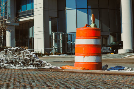 Construction barriers stand near a building while snow covers parts of the ground. A vehicle is parked in the background, indicating an active area.の写真素材