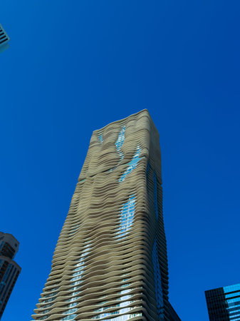 A tall building with a unique wavy design stands in Chicago. The sky is bright and blue. The...