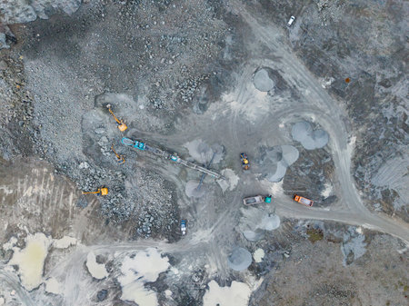 Heavy machinery is at work in a quarry. Workers and equipment are involved in rock extraction and...