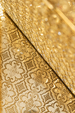 Golden patterns are arranged on a flat surface with detailed designs. Light reflections enhance the...