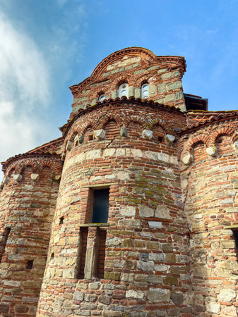 People can see a historic stone church made of brick. The building shows unique architecture with...