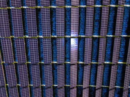 Rows of solar panels are set on a flat roof under a clear blue sky. The sunlight creates a pattern...